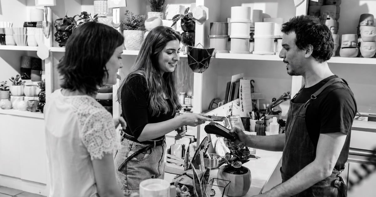 A customer taps to pay at the counter of a homewares shop